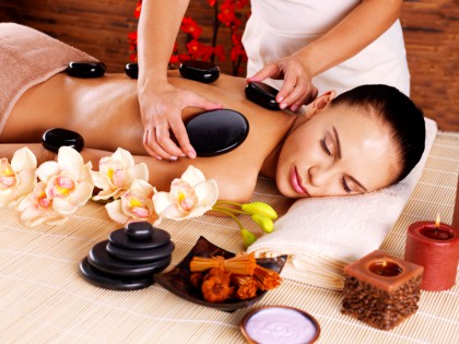 Adult woman having hot stone massage in spa salon