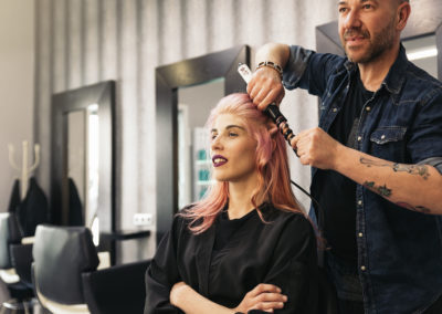 Beautiful woman getting haircut by hairdresser.